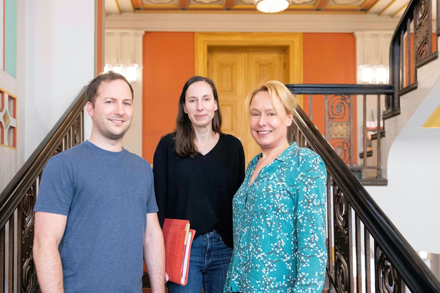 Ein Team - Drei Personen, zwei Frauen, ein Mann nebeneinander im Flur