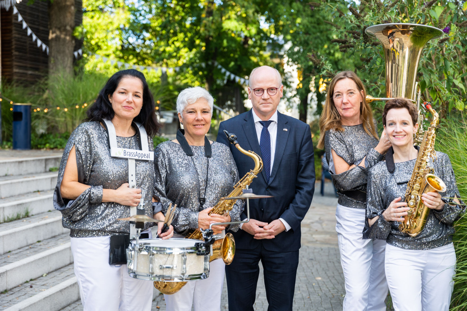 4 Frauen mit Musikinstrumenten stehen mit Mann in einer Gruppe