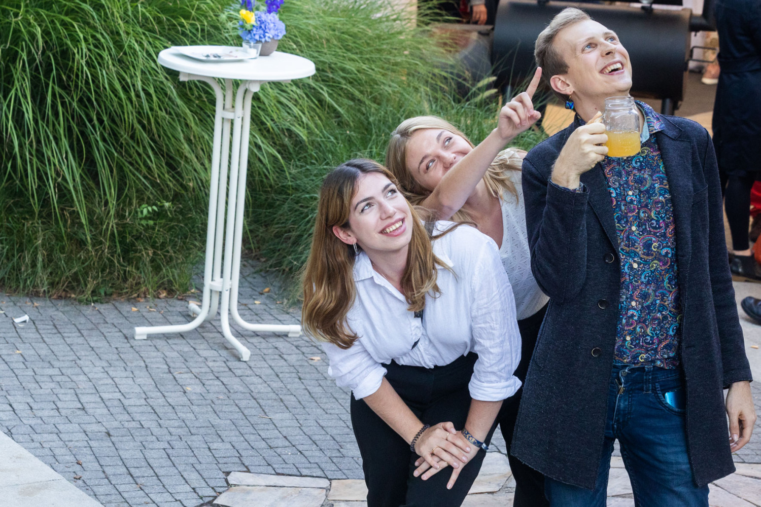 3 lachende Personen schauen in den Himmel