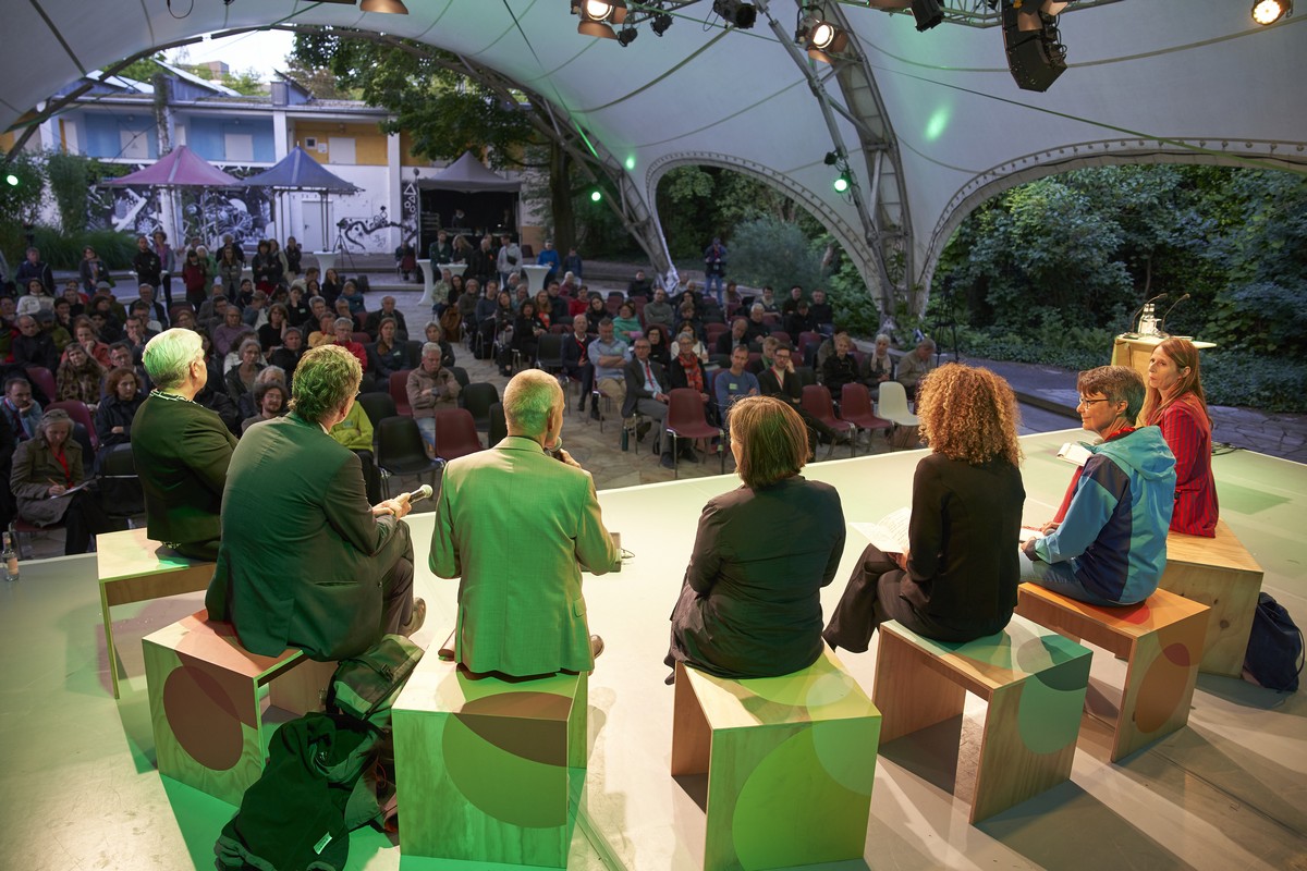 Sieben Personen sitzen auf Hockern auf der Bühne. Sie sind von hinten zu sehen, vor ihnen sieht man das Publikum. Die Personen auf dem Podium sind Dipl.-Ing. Gabriele Pütz, Senator Christian Gaebler, Stefan Richter, Prof. Dr. Stefanie Hennecke, Bezirksstadträtin Dr. Claudia Leistner, Dr. Dorothea Hokema und Ricarda Pätzold (difu)