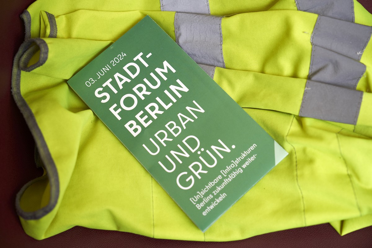 Ein Flyer mit der Überschrift „Stadtforum Berlin Urban und Grün.“ liegt auf einer neongelben Warnweste.