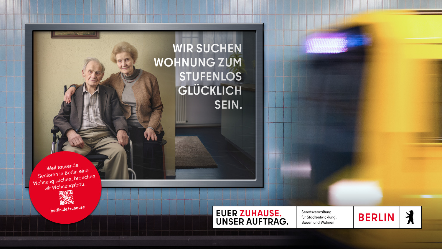 Auf dem Bild ist eine Werbetafel in einer U-Bahn-Station zu sehen. Die Tafel zeigt ein älteres Paar, wobei der Mann im Rollstuhl sitzt. Der Text auf der Tafel lautet: “WIR SUCHEN WOHNUNG ZUM STUFENLOS GLÜCKLICH SEIN.” Im Hintergrund bewegt sich ein Zug.